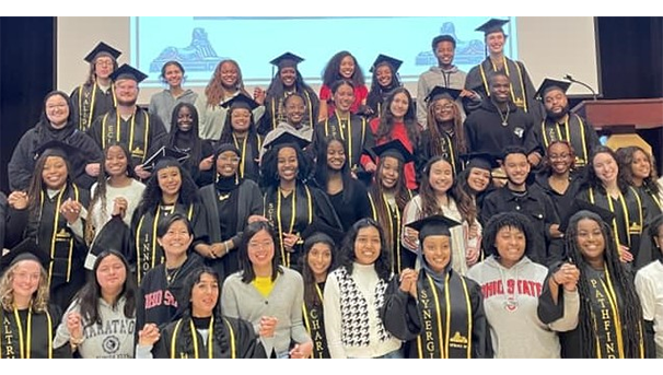 Recent graduates posed before a projection