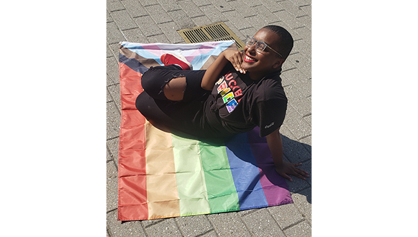 Ose sitting on a pride flag, hand under their chin