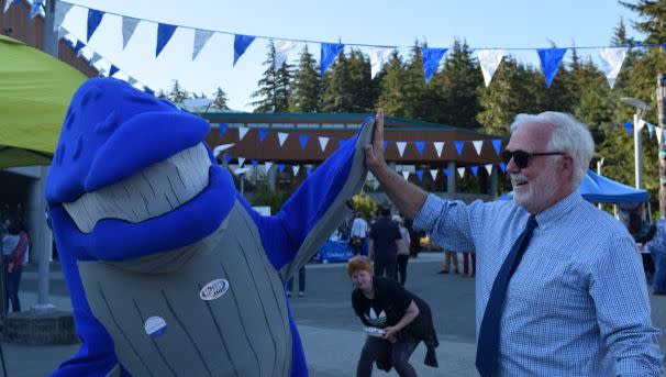 Spike the whale mascot giving a high five to Chancellor Pugh
