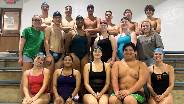 Group of students in swim suits sitting and standing in the bleachers