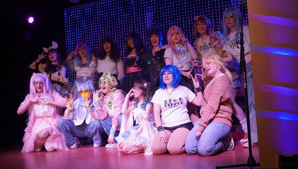 Large group of students dressed in cosplay outfits on a stage
