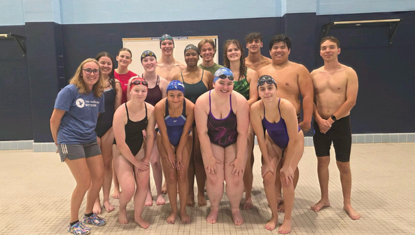 Group of students in swim suits standing on the pool deck