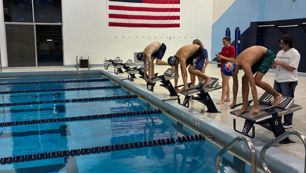 Group of three swimmers preparing to dive into the pool