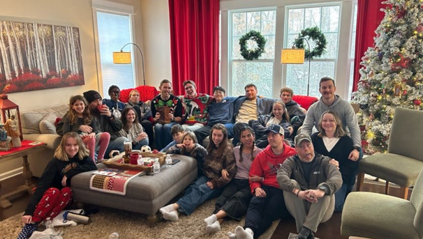 Large group of students in a living room that is decorated for the holidays