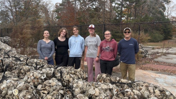 Group of students standing behind bags of oyster shells