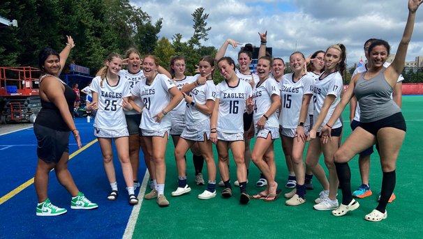 Group of field hockey players smiling and posing for a picture