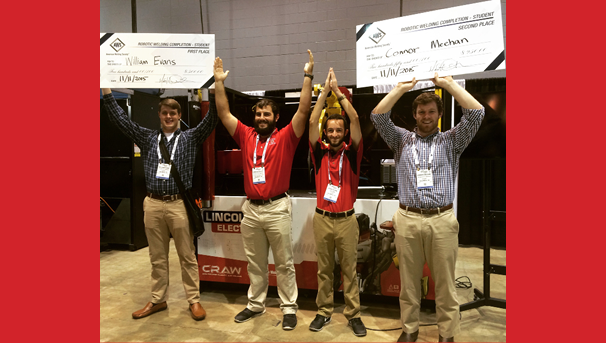 Four individuals spell OHIO with their arms. The two Os hold up large, white checks