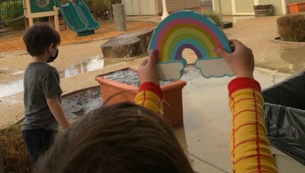 child holding up a rainbow toy