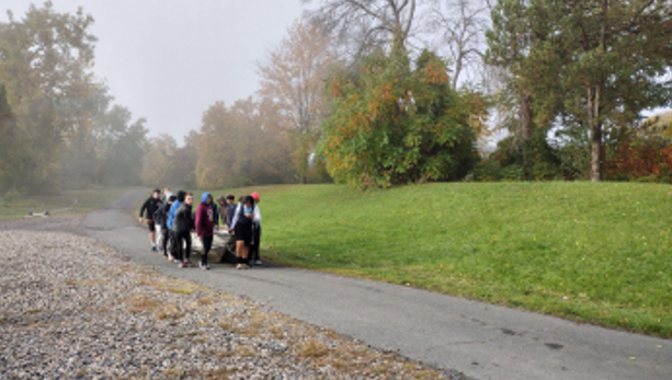 Students dragging a boat along a path near the riverbank