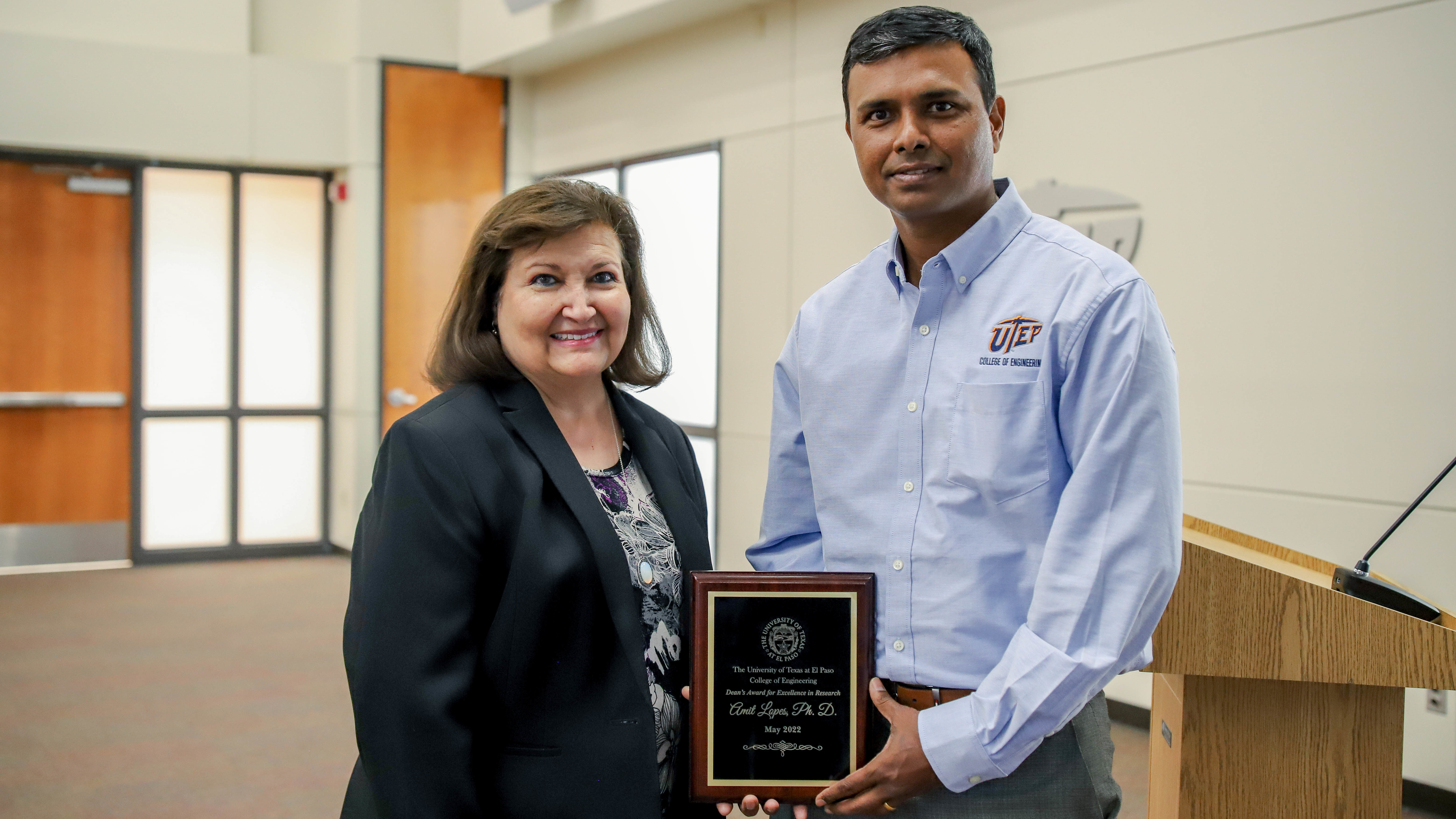 Woman and man posing with Dean's Excellence in Research award plaque