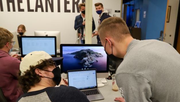 Two students working on a laptop. They converse ideas with one another