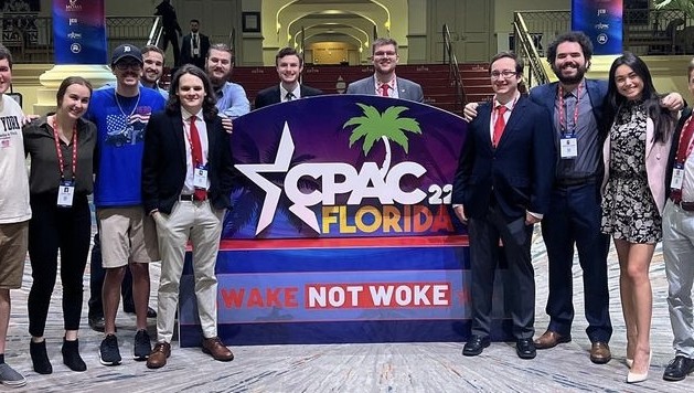 Group of individuals standing by a CPAC Florida sign