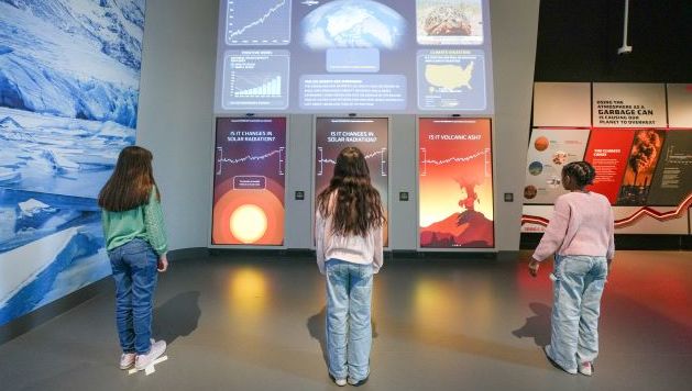 Three young children learning in the Hall of Extinction & Hope at EFM.