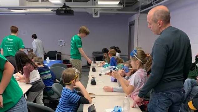 Young students with RPI students and a professor working on a project.