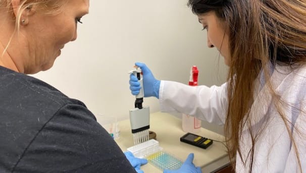 Students working in the lab pipetting a colormetric assay.