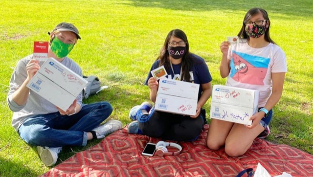 Three masked Blavin Schoalrs with mail packages and gift cards