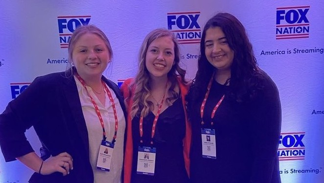 Three individuals standing together smiling