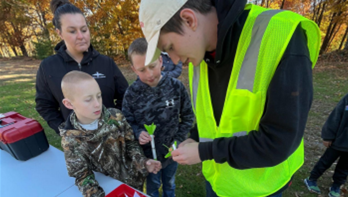 A student helping some kids with a model rocket.