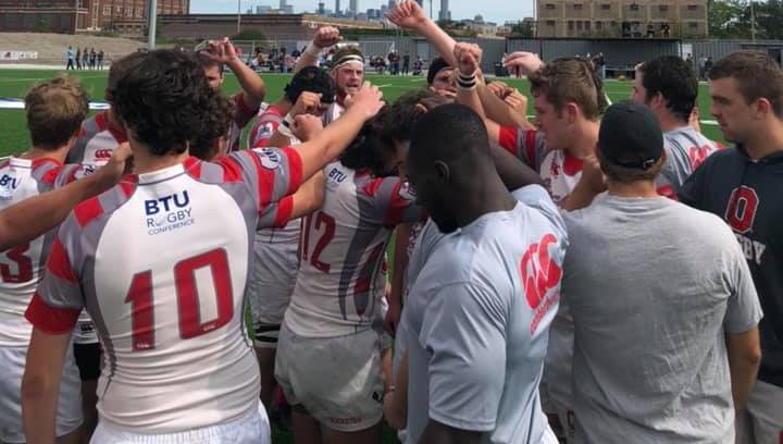 The Rugby team huddled together, holding their fists in the air