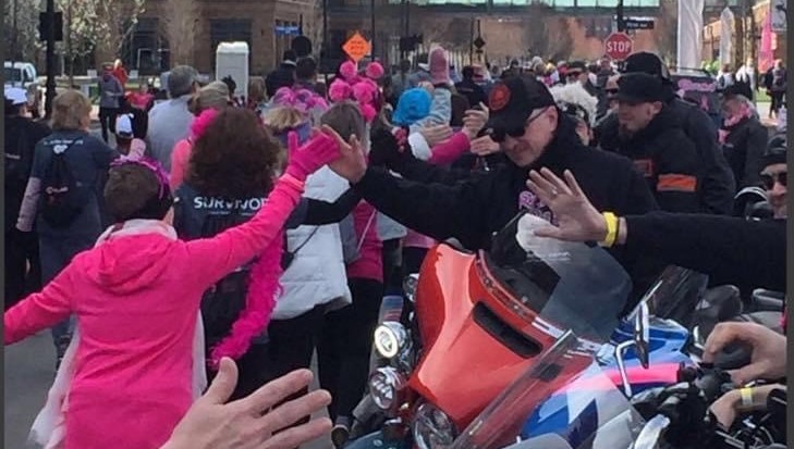 Motorcyclists high-fiving race participants as they go by