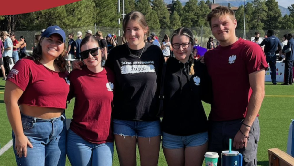 A group of students stand behind a table at the NAU Club Fair.
