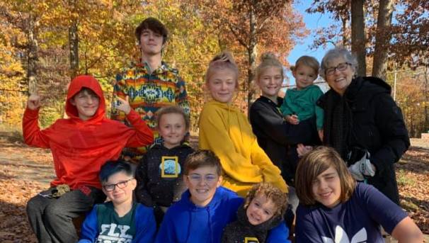 Ellen McKee and her grandchildren. They sit before fallen leaves and orange trees
