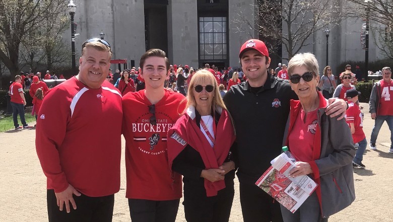 Five buckeye fans ranging in age pose close together in front of the Shoe
