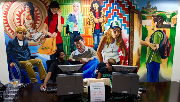 Photo of students in the UNT Multicultural Center with mural behind them.