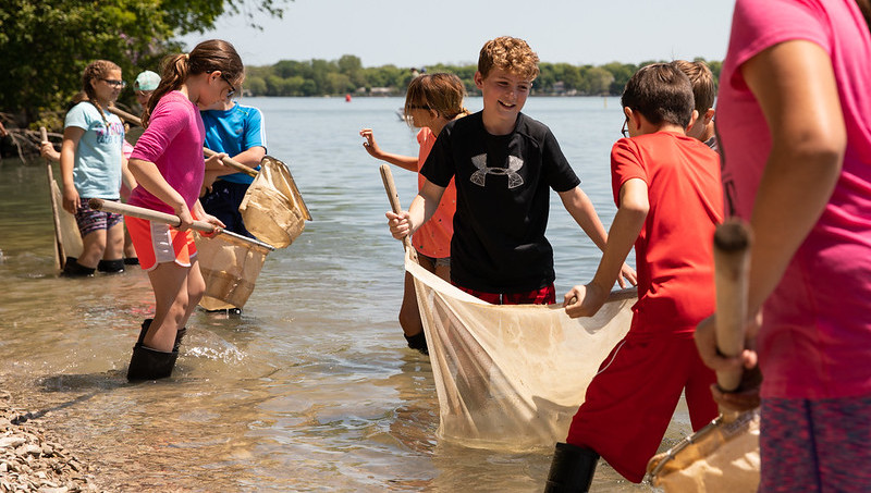 A group of children in the river. They are holding large nets within the water