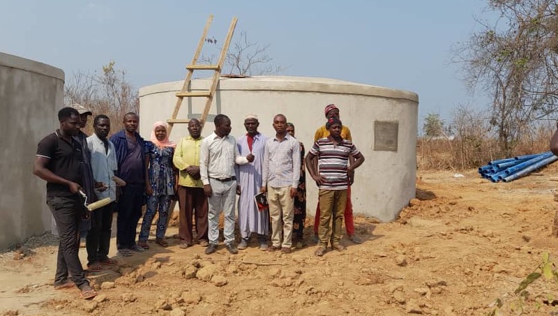 Members of the Sunuka community in front of the final two storage tanks that were built.