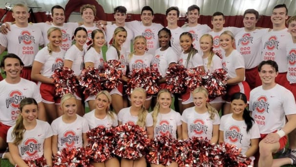 The Cheer squad sitting inside the practice tent, posting together for a picture