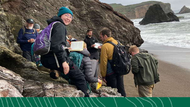 Students and professor pose near a trail sign on a hiking path