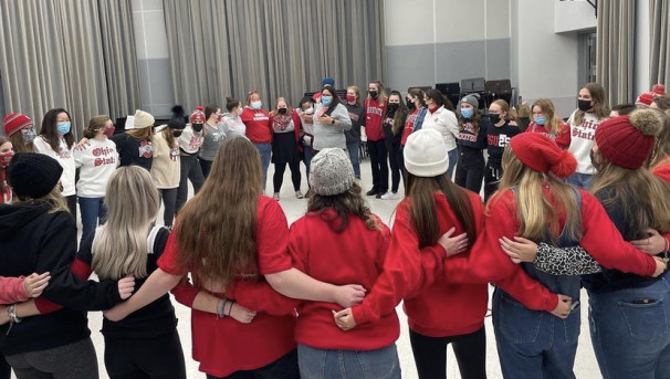 Women's Glee Club members standing in a circle linking arms while singing