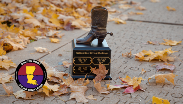 Golden Boot Trophy held up by two hands with Old Main in the background