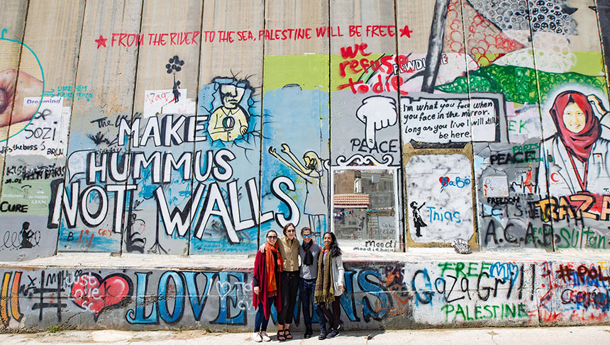 Pal-Trek participants pose near the street-art covered West Bank barrier wall.