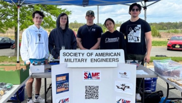 Five students posing with Society of American Military Engineers trifold informational poster.