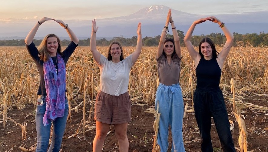 Four individuals in a field holding up their arms spelling OHIO