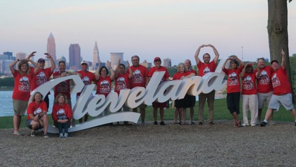 Alumni posing around the Cleveland sign, doing O H I O with their arms