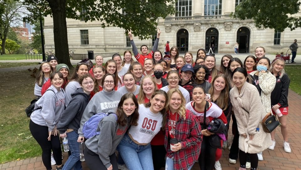 Women's Glee Club members smiling for a group photo outside Thompson library