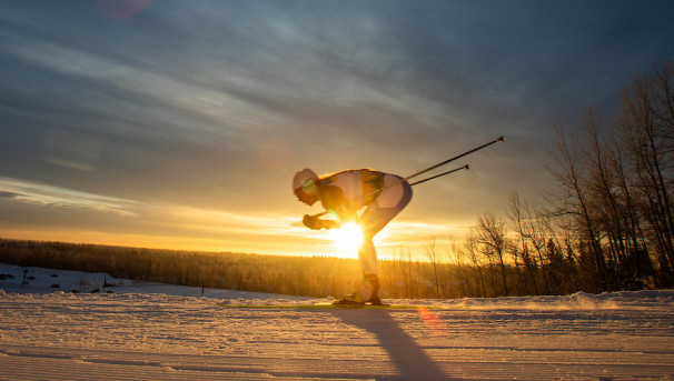 Nanoook skier racing in front of the sunset on the UAF Competition trails.