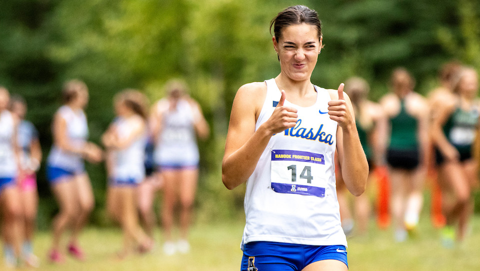Women's Cross Country athlete gives a thumbs up during a 2023-24 season meet.