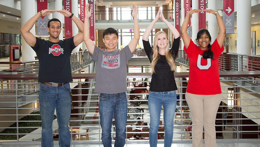Four students holding their arms to spell OHIO. They are posed on the second floor of The Union