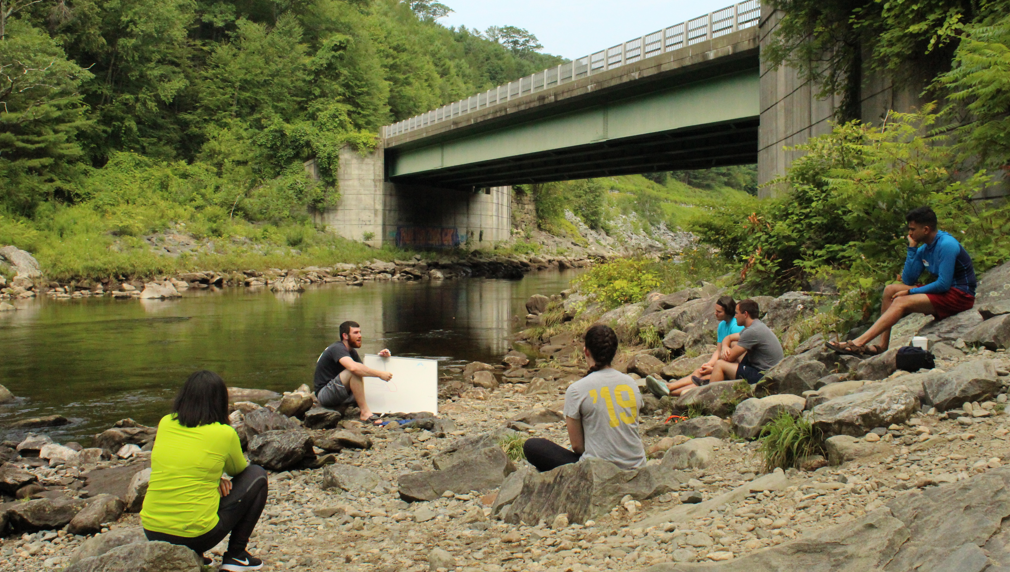 Students sitting by the edge of a river