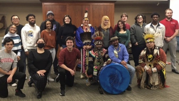 A group of students from SACNAS pose with people in native outfits