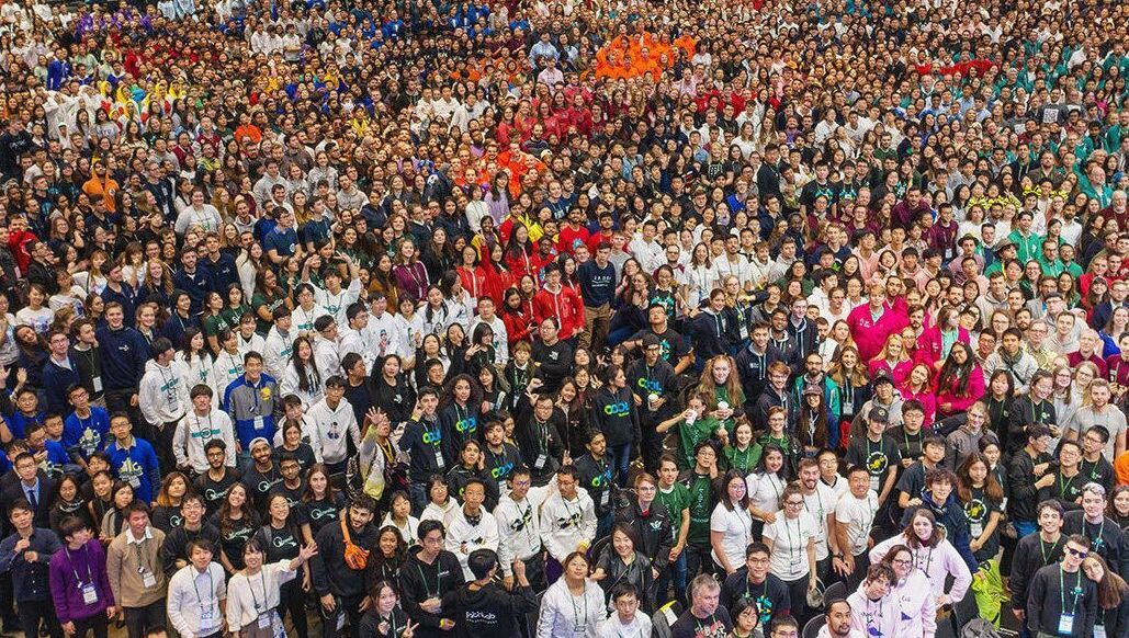 2019 iGEM Giant Jamboree. Many groups surround the floor, all wearing various team colors