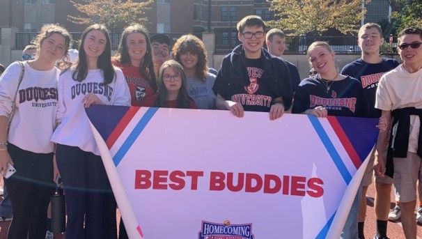 people standing in front of sign that says 'best buddies'