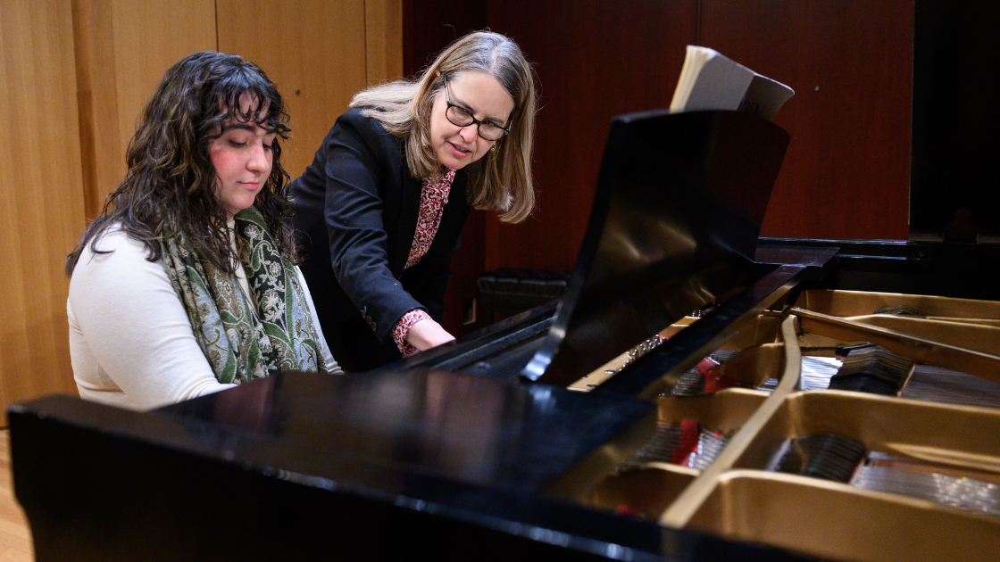 Professor assisting student in playing the piano