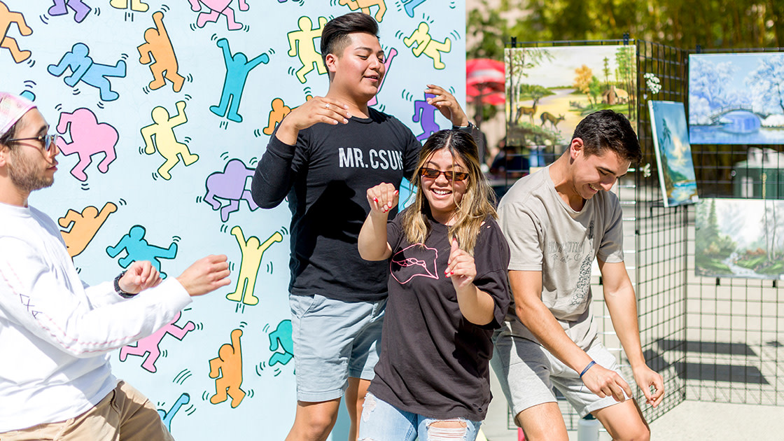 Students posing with art backdrop.