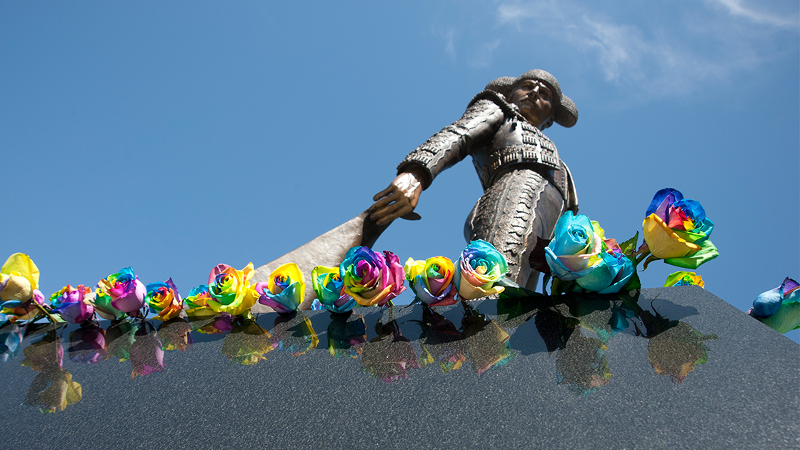 Image of the Matador statue with rainbow roses around the base.