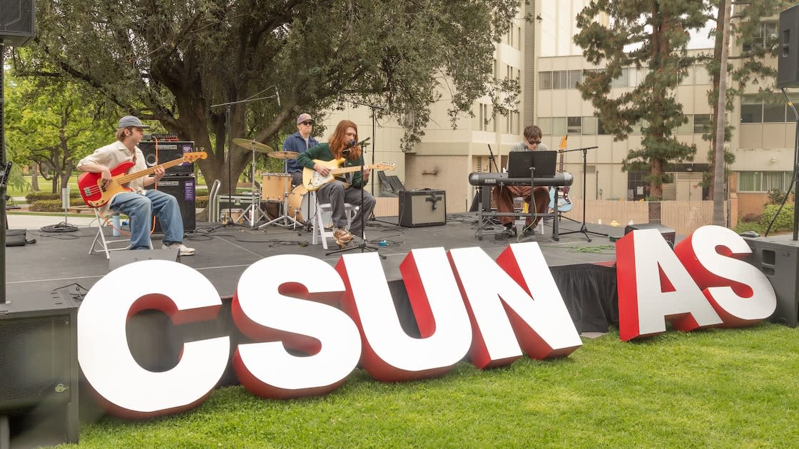 Student band performs live outdoors at CSUN AS event near campus building.